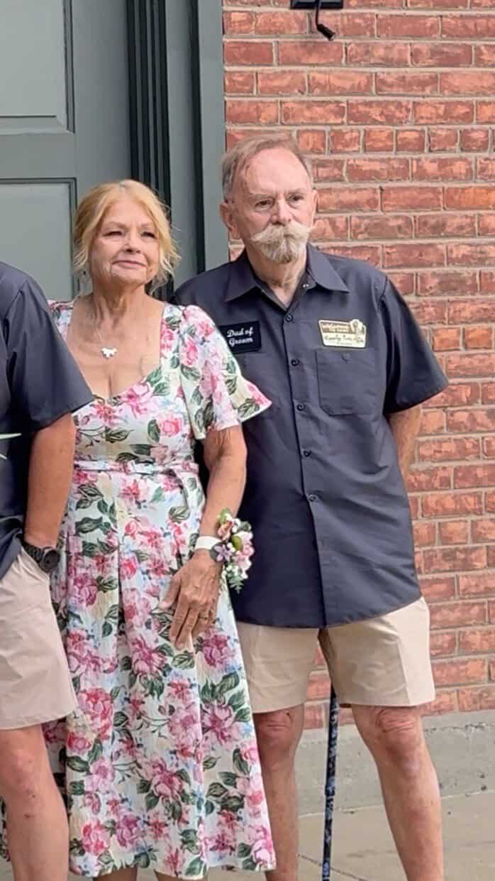 Elderly couple at Camp Happily Ever After event outside brick building.