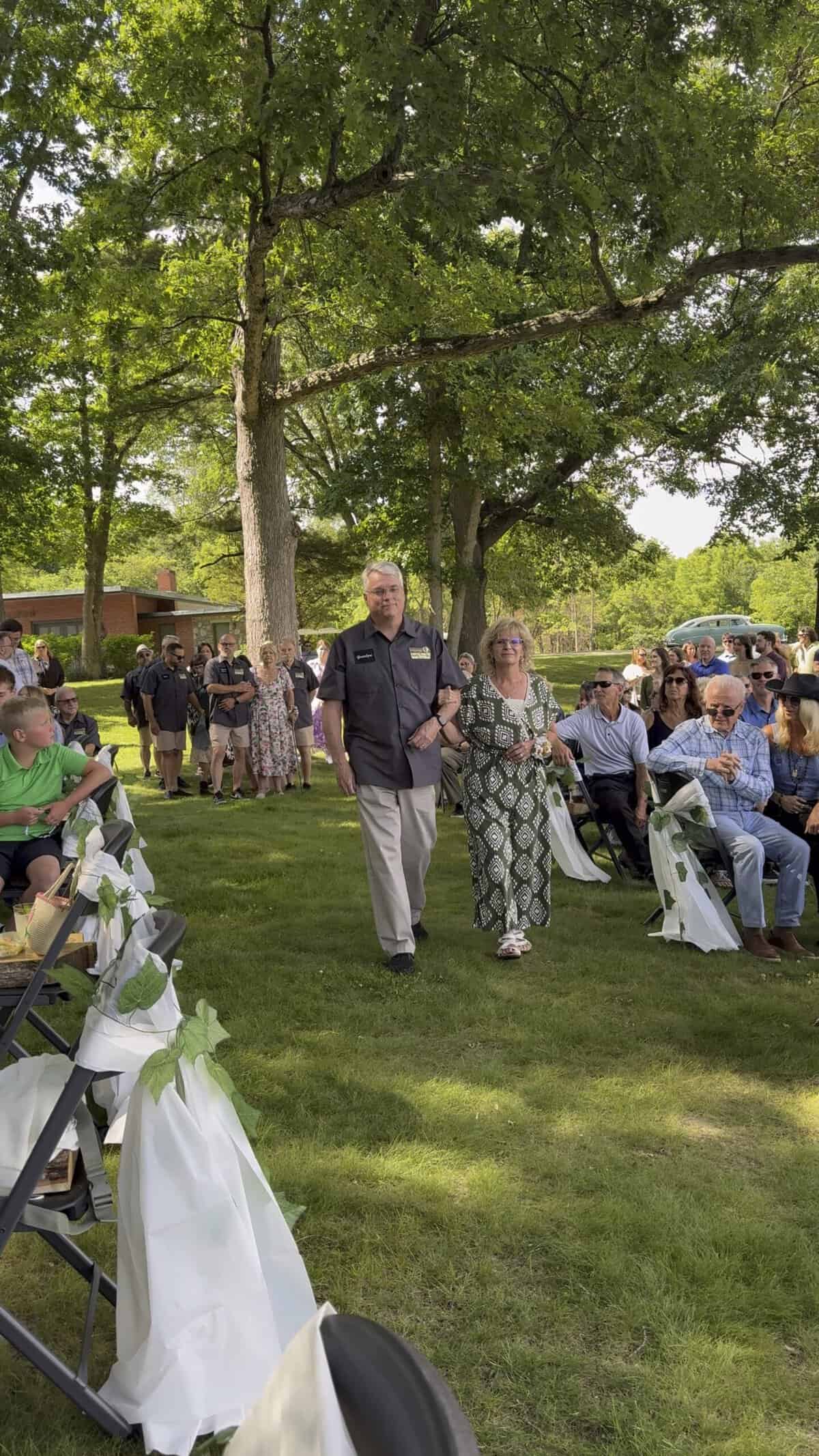 People enjoying outdoor event at Camp Happily Ever After with trees and seating.